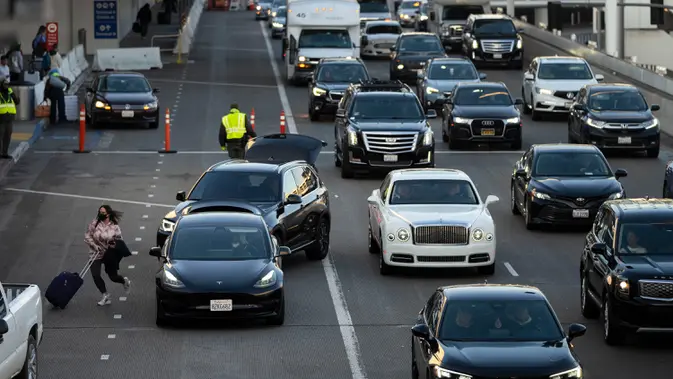 Seorang wanita bergegas ke terminal setelah diturunkan di Bandara Internasional Los Angeles, Los Angeles, Amerika Serikat. (AP Photo/Jae C. Hong)