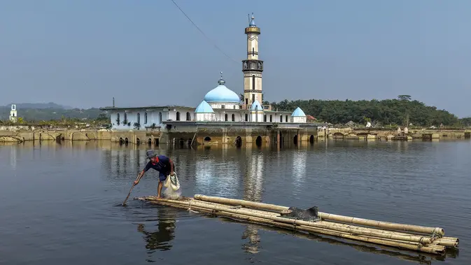 Seorang pria mengendalikan rakit bambunya di kawasan Bendungan Karian yang mengering di Kampung Somang, Lebak, Banten, Kamis (30/7/2026). (AFP/ Bay Ismoyo)