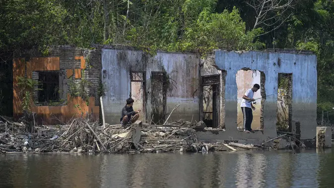 Warga memancing diantara puing bangunan rumah yang kembali muncul di kawasan Bendungan Karian yang mengering di Kampung Somang, Lebak, Banten, Kamis (30/7/2026). (AFP/ Bay Ismoyo)