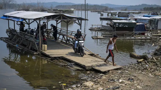 Warga mengarahkan rakit penyeberangan ke tepi bendungan  yang menyusut di dekat Kampung Somang di Lebak, Banten, Kamis (30/7/2026). (AFP/ Bay Ismoyo)