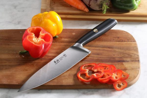 A chefs knife on a cutting board with sliced and whole bell peppers Credit: Amazon