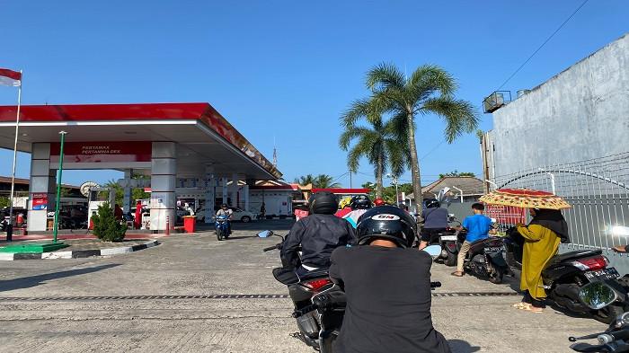ANTREAN BBM MENGULAR – Seorang pengendara sepeda motor membawa payung saat mengantre pengisian BBM subsidi jenis Pertalite di SPBU Kampung Opas, Kota Pangkalpinang, Selasa (14/7/2026). Antrean kendaraan mengular hingga keluar area SPBU dan telah terjadi sejak beberapa hari terakhir.