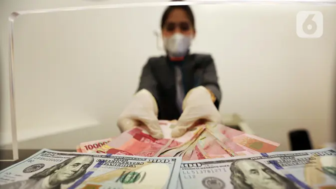 Karyawan menunjukkan uang rupiah dan dolar AS di Jakarta. (Liputan6.com/Johan Tallo)