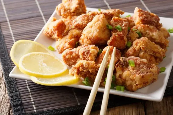 Portion fried chicken karaage with lemon and onion close-up on a plate on the table. horizontal