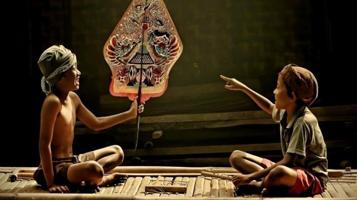 BERMAIN WAYANG- Ilustrasi dua orang anak sedang asyik bermain wayang kulit.