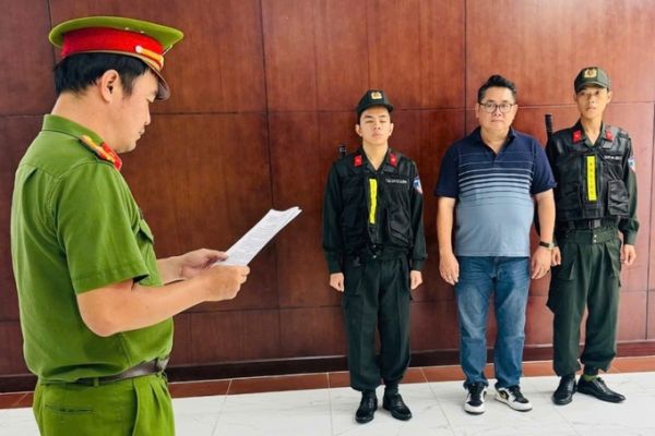 Nguyen Thanh Hiep (in a T-shirt) listens as police read the decision to prosecute him. Photo by police