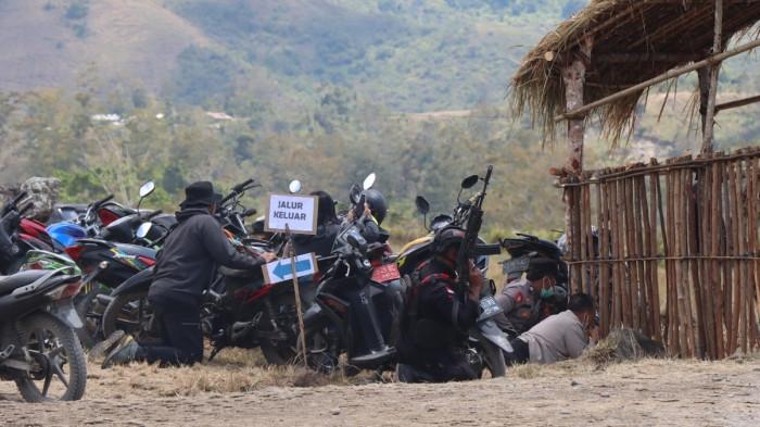 MENGAMANKAN DIRI – Aparat kepolisian dan masyarakat yang menyaksikan Festival Budaya Lembah Baliem di Kabupaten Jayawijaya, Provinsi Papua Pegunungan mencari perlindungan untuk mengamankan diri dari balik gubuk menyusul adanya penembakkan yang mengakibatkan dua warga mengalami luka, Sabtu (8/8/2026).