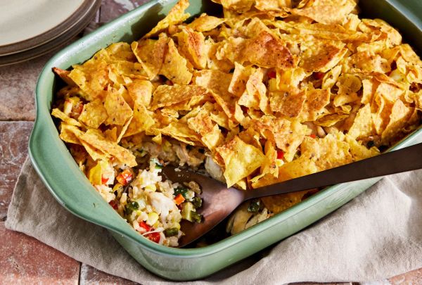 Green chile rotisserie chicken casserole recipe in a light green baking dish, with a serving spoon spooning out a portion of the casserole Credit: Photographer: Jen Causey, Food Stylist: Melissa Gray