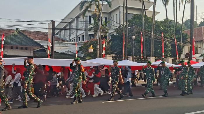 FESTIVAL MERAH PUTIH - Warga berjalan di bawah bendera raksasa saat kirab bendera dalam Festival Merah Putih di Kota Bogor, Minggu (9/8/2026).