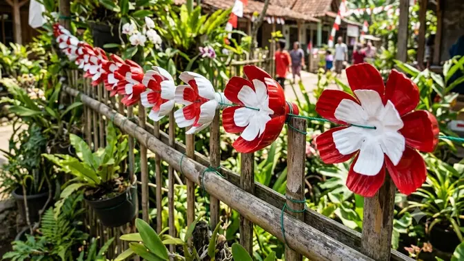 Bunga Plastik dari Bagian Bawah Botol/ dekorasi jalan kampung dari botol bekas bertema kemerdekaan (AI generated)