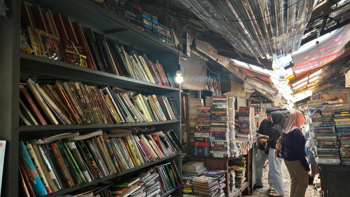 PASAR BUKU BEKAS SURAKARTA - Suasana lapak buku bekas dengan berbagai koleksi buku yang tersusun di rak dan bertumpuk di sepanjang area pasar, Sabtu (8/8/2026). Pengunjung tampak menyusuri lapak untuk mencari buku yang mereka inginkan.