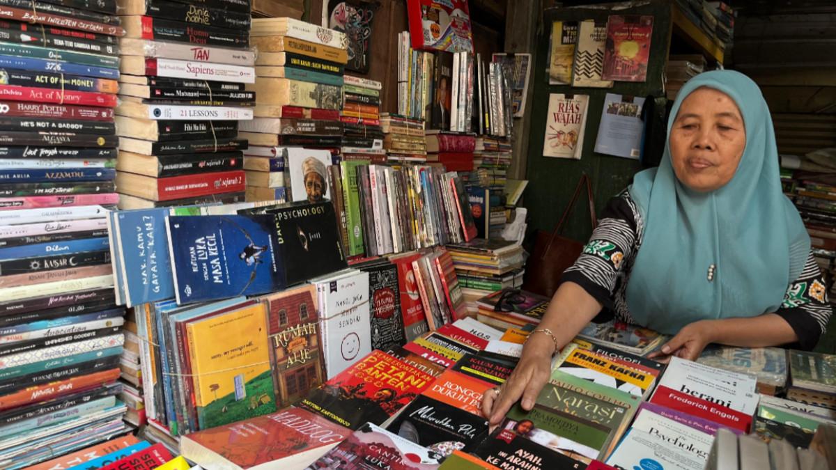 PASAR BUKU BEKAS ALUN-ALUN SURAKARTA - Potret seorang ibu penjual buku bekas sedang menata dan merapikan koleksi buku dagangannya di kios Pasar Buku Bekas Alun-Alun Lor Surakarta, Sabtu (9/8/2026).