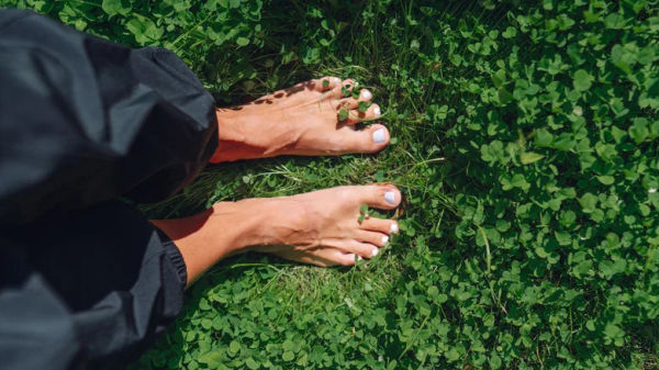 Person's feet in field of grass and clovers