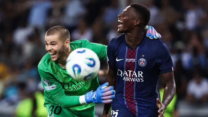 Pemian PSG, Nuno Mendes (kanan) bersama kiper Lucas Chevalier merayakan kemenangan dalam babak adu penalti laga final UEFA Super Cup melawan Tottenham Hotspur yang berlangsung di Bluenergy Stadium, Udinese, Italia, Rabu (13/08/2025) waktu setempat. (AFP/Franck Fife)
