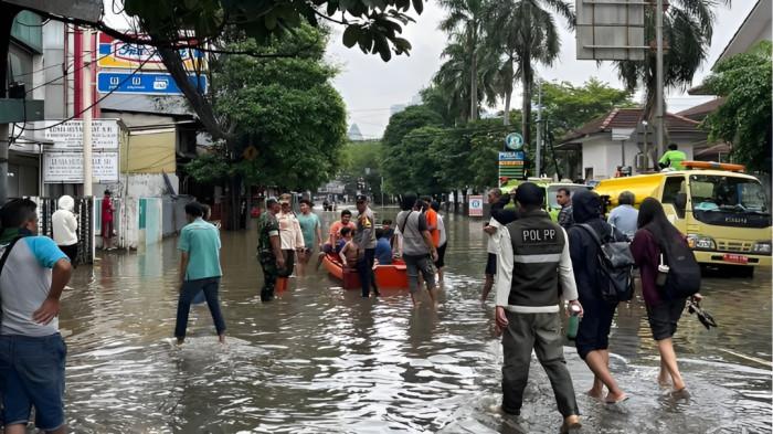 BANJIR- Satu kawasan permukiman di Indonesia sedang dilanda banjir setelah diguyur hujan lebat. Petugas membawa perahu karet untuk mengevakuasi warga.