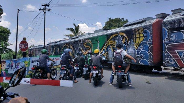 Pengendara berada di depan palang pintu saat kereta api tengah melintas di kawasan Pasar Nongko, Jalan Hasanudin, Kecamatan Banjarsari, Solo, Senin (11/3/2019). 