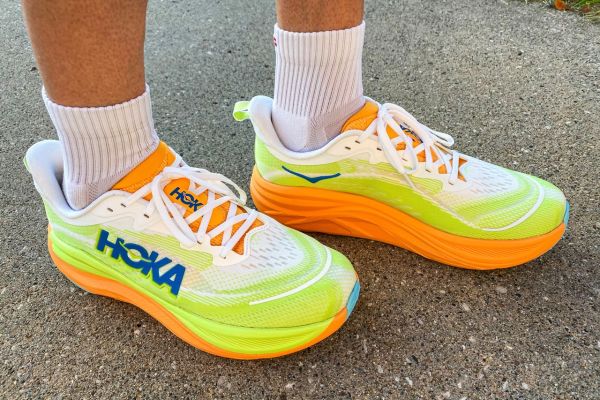 A person stands outside while wearing the HOKA Men's Skyflow Running Shoes Credit: EatingWell