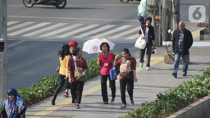 Warga beraktivitas menggunakan payung saat suhu udara mencapai 35 derajat Celcius di Kawasan Jalan MH Thamrin, Jakarta. (Liputan6.com/Helmi Fithriansyah) Event