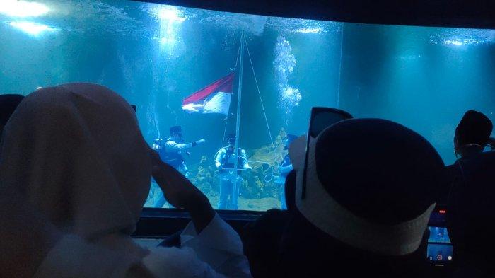 Pengunjung menghormati pengibaran bendera di dasar akuarium terpanjang di Aquarium Indonesia Pangandaran, Sabtu (17/8/2024).