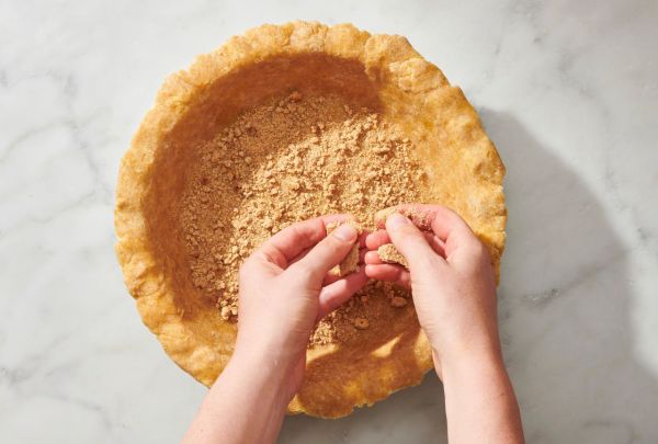 Hands adding crumb topping to a pie crust Credit: Photographer: Diana Christruga