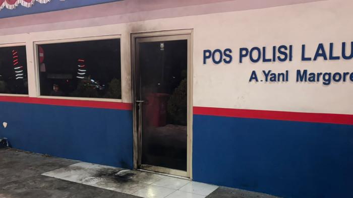 BEKAS MENGHITAM - Penampakan Pos Polisi Lalu Lintas Jalan Ahmad Yani Margorejo, Kecamatan Gayungan, Kota Surabaya, diduga jadi sasaran pelemparan bom molotov oleh orang tak dikenal pada Sabtu malam (15/8/2026). Terlihat ada bekas ledakan menghitam di pintu masuk bangunan tersebut.