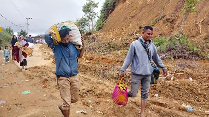 WARGA BERJALAN KAKI - Warga berjalan kaki memangku logistik di jalan KKA tepatnya di Kampung Burni Pase Kecamatan Permata, Bener Meriah, Rabu (3/12/2025).