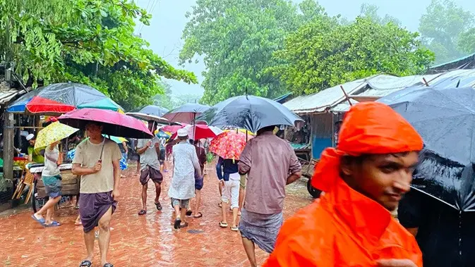 Warga berjalan di tengah guyuran hujan di kamp pengungsi Rohingya di Cox’s Bazar, Bangladesh, pada Selasa (7/72026). (Dok. AP/Shamimul Islam Faisal)