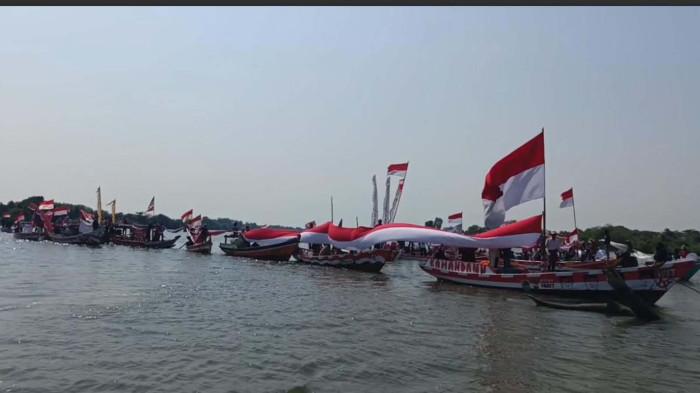 BENTANGKAN BENDERA - Suasana karnaval perahu bentangkan bendera sepanjang 45 meter di Sungai Bengawan Solo, Kecamatan Ujungpangkah, Kabupaten Gresik, Jawa Timur, Minggu (16/8/2026).