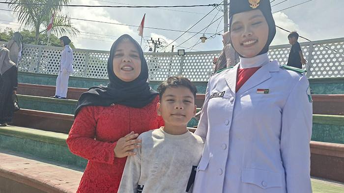 Saskia, siswa SMAN 1 Bireuen bersama ibu da adiknya dan sedang membawa baki. SERAMBI/YUSMANDIN IDRIS