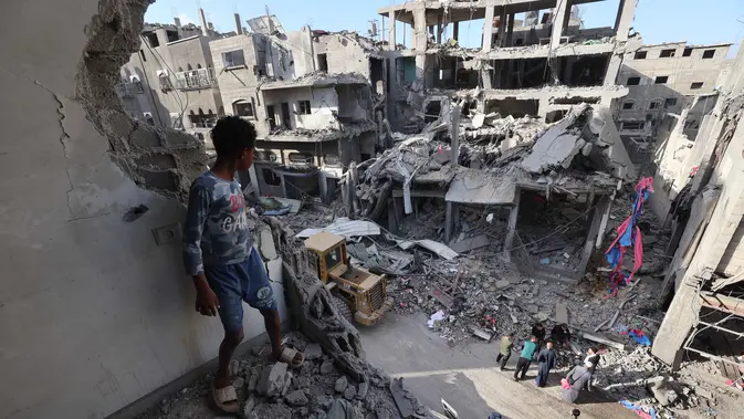 Seorang anak laki-laki Palestina yang mengungsi melihat bangunan yang rusak akibat serangan Israel di kamp pengungsi Maghazi, Jalur Gaza Tengah pada Kamis 21 Mei 2026. (Eyad Baba/AFP)
