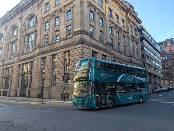 Modern Glasgow Airport Express bus on a street beside historic sandstone architecture Modern Glasgow Airport Express bus on a street beside historic sandstone architecture