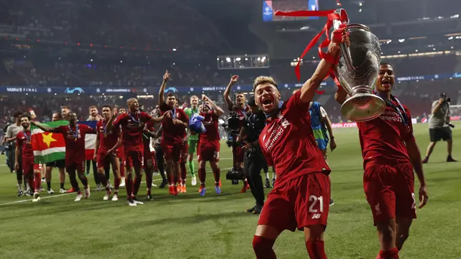 Pemain Liverpool, Alex Oxlade-Chamberlain dan Rhian Brewster mengangkat trofi juara Liga Champions 2019 usai menaklukkan Tottenham Hotspur di Stadion Wanda Metropolitano, Madrid, Minggu (2/6). Liverpool menang 2-0 atas Tottenham Hotspur. (AP/Bernat Armangue)