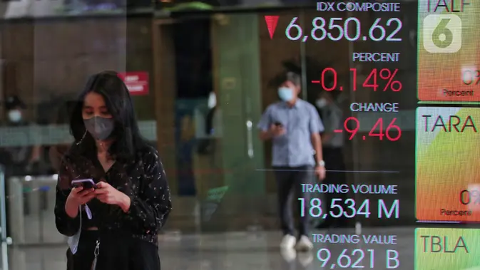Karyawan melintasi layar yang menampilkan Indeks Harga Saham Gabungan (IHSG) (Liputan6.com/Angga Yuniar)