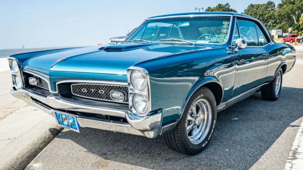 A rare blue 1967 Pontiac GTO two-door parked by the ocean.