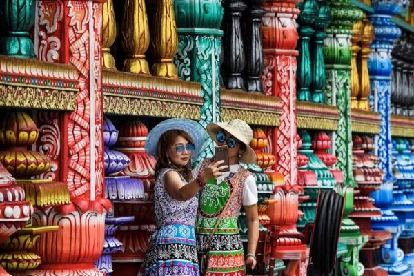 Two tourist take pictures at a temple in Batu Caves, near Kuala Lumpur on August 6, 2019. Photo by AFP