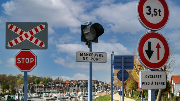 Several French road signs with waterway in background
