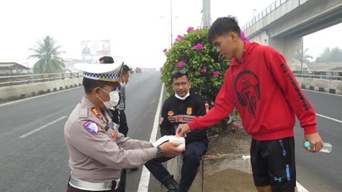 BAGI BAGI MASKER --- KBO Satlantas Polrestabes Palembang, AKP Bambang Haryanto (tengah), bersama petugas Dinas Perhubungan (Dishub) Palembang membagikan masker gratis kepada warga yang beraktivitas di kawasan Car Free Day (CFD) di pangkal flyover depan DPRD Kota Palembang, Minggu (23/8/2026). Aksi spontan ini dilakukan menyusul kondisi udara di Kota Palembang yang diselimuti kabut asap pekat dan udara lembab sejak subuh.