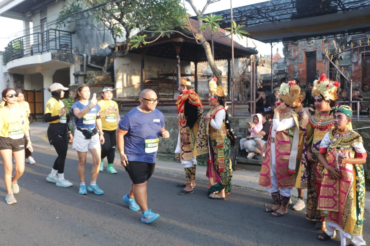 Peserta Maybank Marathon 2026 berfoto dengan penari yang memberikan semangat saat melintasi rute di wilayah Gianyar