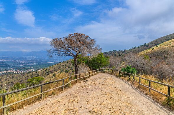 Road with wooden fence on mountain hill Serra Gelada natural park and aerial view of La Nucia Hills valley in summer day, Valenc Road with wooden fence on mountain hill Serra Gelada natural park and aerial view of La Nucia Hills valley in summer day, Valenc