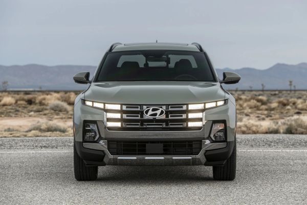 Front view of a gray Hyundai SUV with illuminated LED grille lights on a desert road.