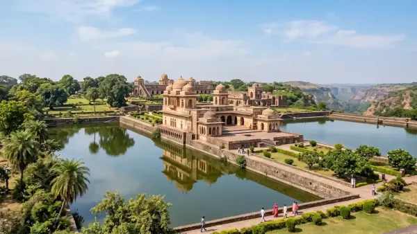 Ancient Jahaz Mahal palace reflecting in surrounding water tanks amid lush gardens and scenic hills under blue sky.