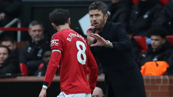 Pelatih sementara Manchester United asal Inggris, Michael Carrick, berbicara dengan gelandang Manchester United asal Portugal bernomor punggung 08, Bruno Fernandes, selama pertandingan Liga Inggris antara Manchester United dan Manchester City di Old Trafford, Manchester, barat laut Inggris, pada 17 Januari 2026. (Darren Staples/AFP)