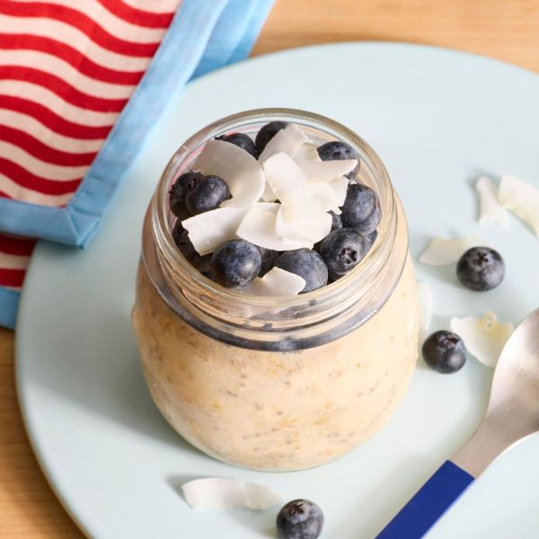 A jar of overnight oats topped with blueberries and coconut shavings on a plate Credit: Photographer: Stacy K. Allen, Food Stylist: Jennifer Wendorf, Prop Stylist: Phoebe Hausser