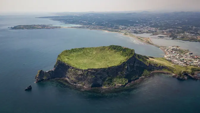 Pemandangan udara Seongsan Ilchulbong, atau 'Puncak Matahari Terbit', formasi batuan vulkanik di pulau Jeju, Korea Selatan (10/5/2019). Pulau Jeju adalah pulau terbesar di Korea dan terletak di sebelah selatan Semenanjung Korea. (AFP Photo/Ed Jones)
