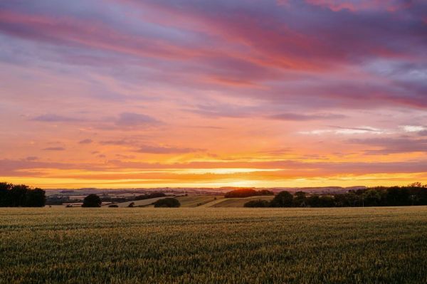 Dramatic colorful sunset sky above agricultural fields in countryside Dramatic colorful sunset sky above agricultural fields in countryside