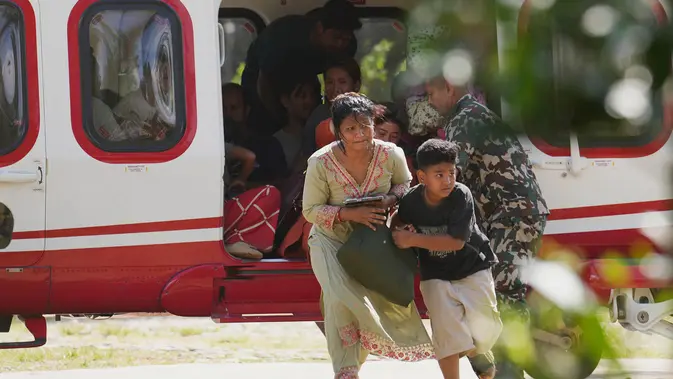 Tentara membantu sebuah keluarga turun dari helikopter setelah mereka diselamatkan dari wilayah yang terdampak banjir bandang di distrik Nuwakot, Nepal, Jumat, 28 Agustus 2026. (Foto AP/Rajesh Kumar Singh)