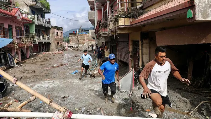 Warga setempat berjalan melewati rumah-rumah yang terendam lumpur akibat banjir bandang di Devighat, Kotamadya Bidur, Distrik Nuwakot, Nepal, Kamis, 27 Agustus 2026. (AFP/Prabin Ranabhat)