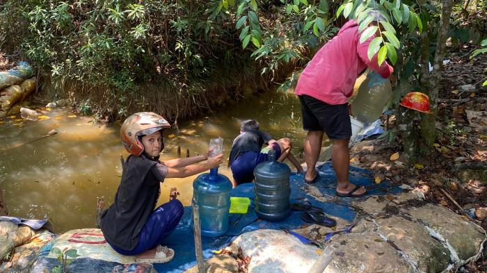 BERBURU AIR - Warga berburu air yang masih layak pakai lalu mengisinya ke galon dan jeriken di parit kawasan Marina Sekupang Batam, Sabtu (29/8/2026) siang.