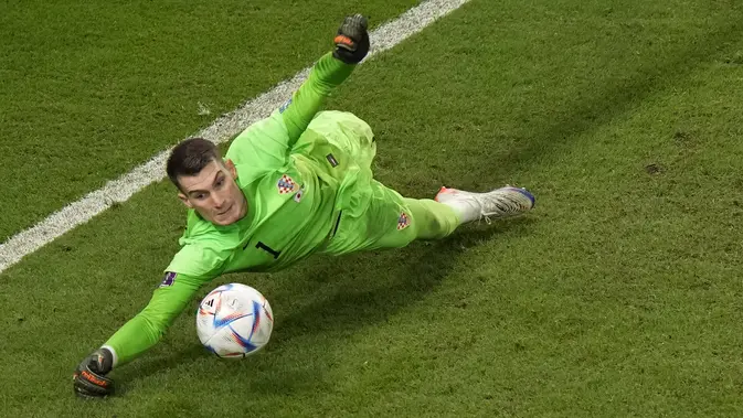 Kiper Kroasia, Dominik Livakovic melakukan penyelamatan penalti saat laga 16 besar Piala Dunia 2022 melawan Jepang yang berlangsung di Al Janoub Stadium, Senin (05/12/2022). (AP/Luca Bruno)