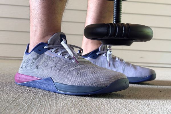 View of person's ankles standing in Flux Footwear Adapt Graphene XT cross-training shoes with adjustable kettle bell hanging between. Credit: EatingWell/Dillon Evans
